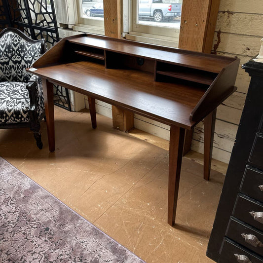Wooden L-shaped desk in a room with a chair and window