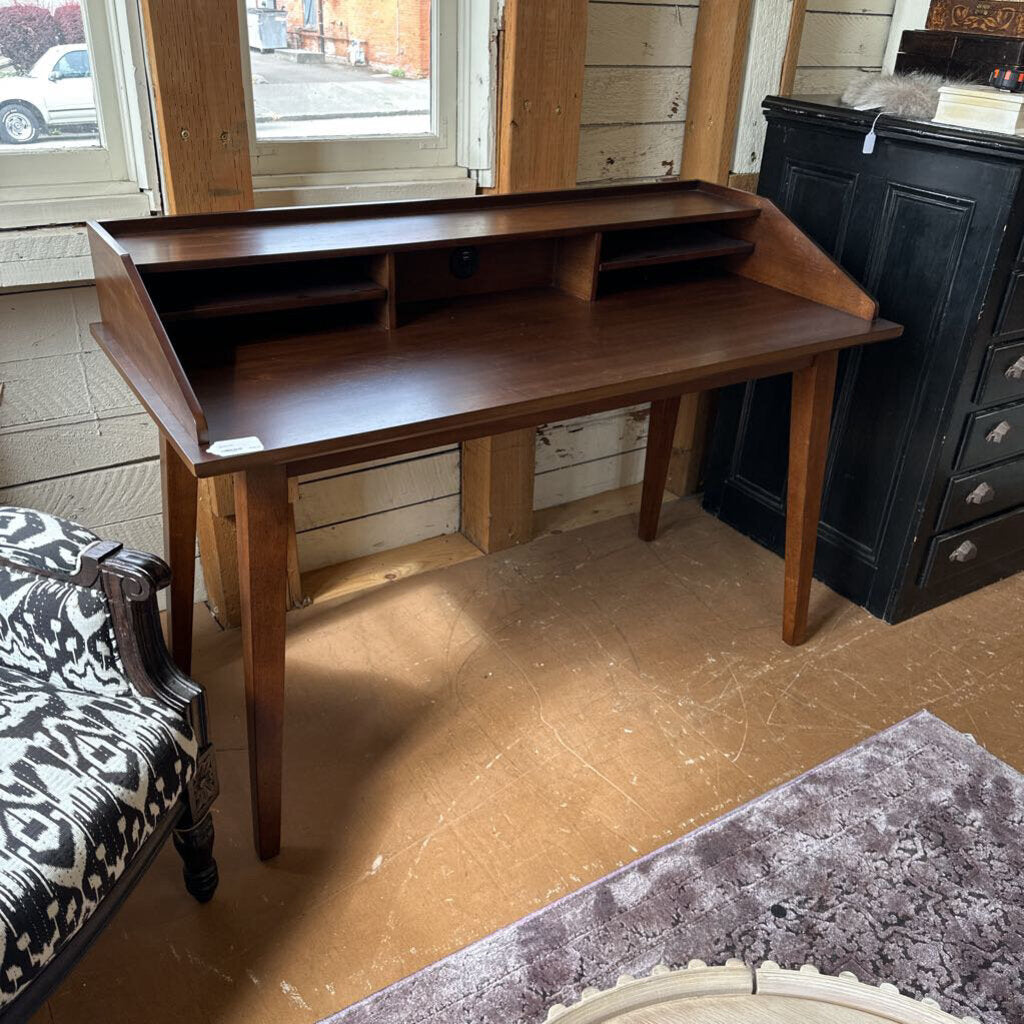 Wooden desk in a room with a window and furniture.