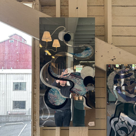 Person taking a mirror selfie in a store with abstract art design on the mirror