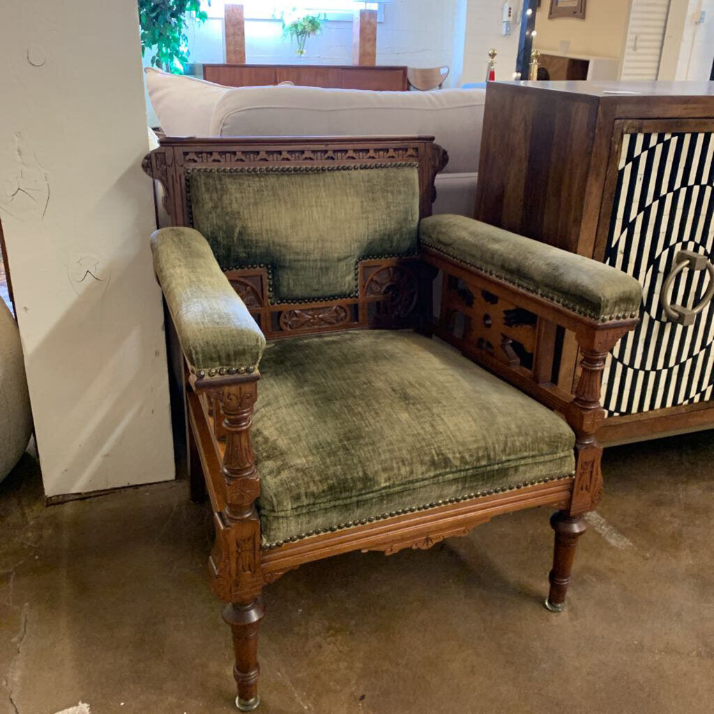 Vintage wooden chair with green velvet upholstery in a room setting.