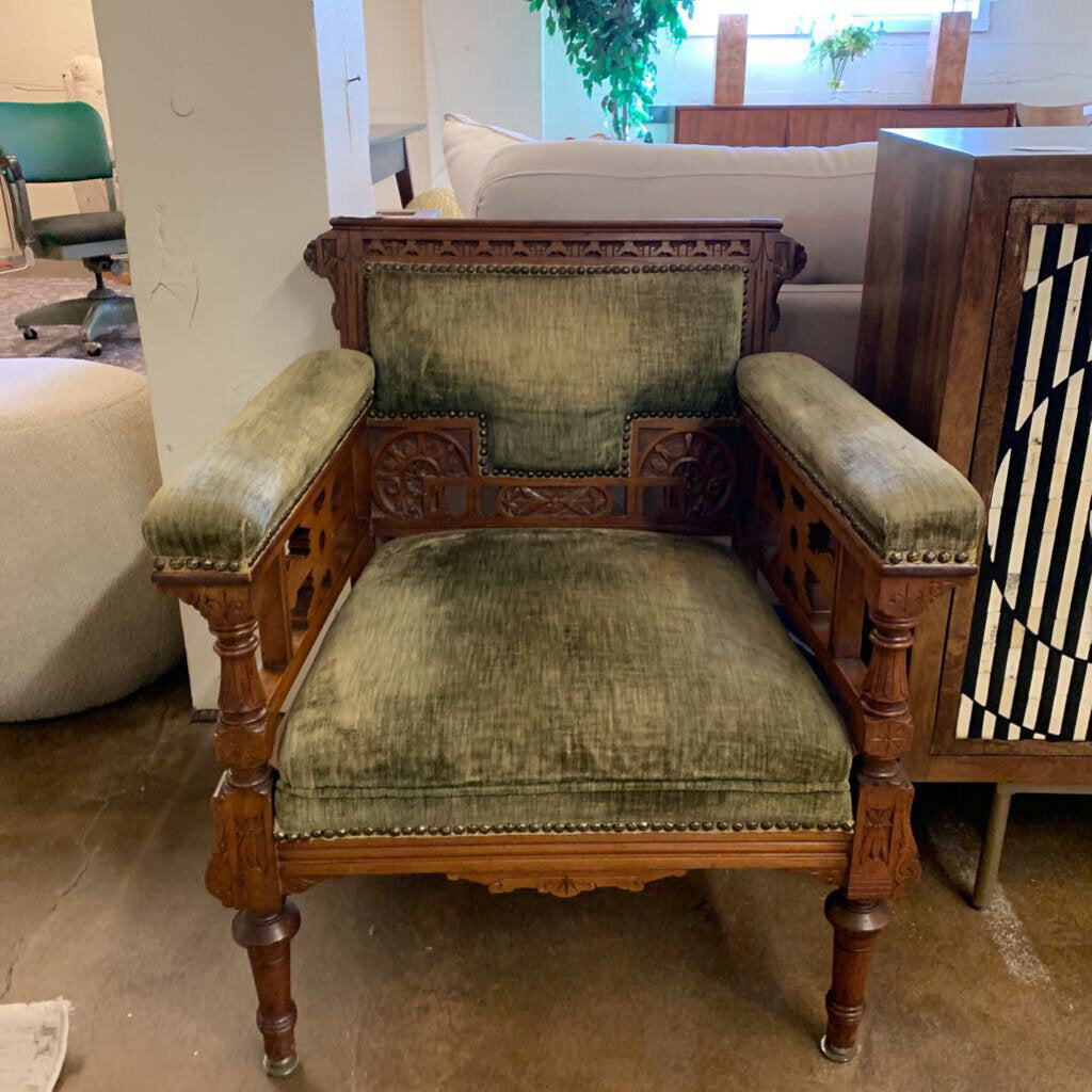Vintage wooden chair with green velvet cushions in a room setting.