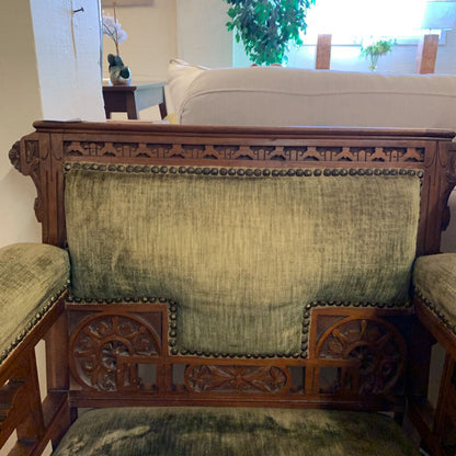 Vintage wooden bench with green cushioned seats and backrest in a room setting.