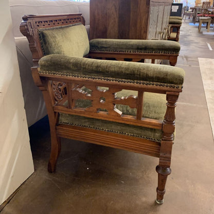 Vintage wooden chair with green cushioned seat and backrest in a showroom setting.