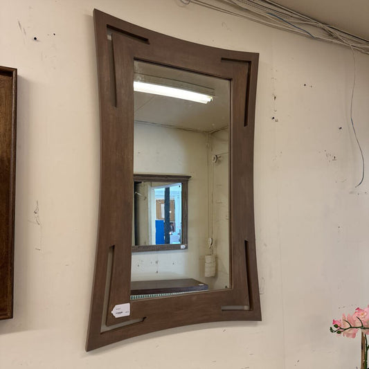 Wooden-framed mirror on a wall with a visible light fixture.