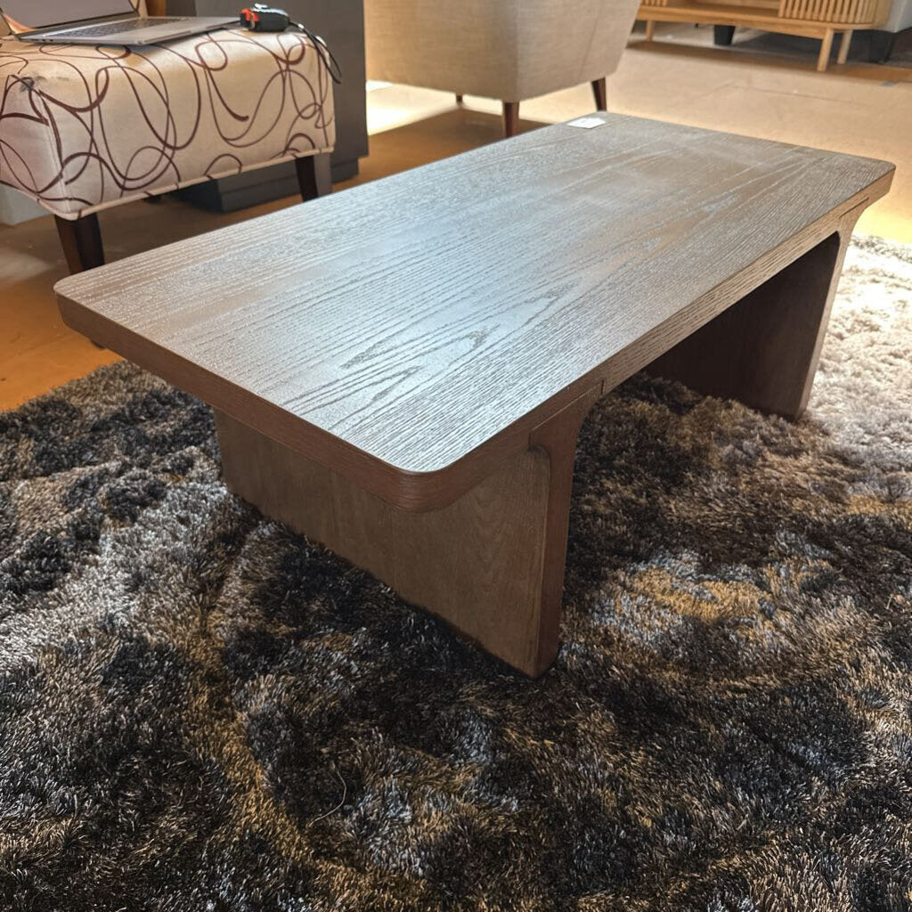 Wooden coffee table on a textured rug in a living room setting