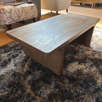 Wooden coffee table on a textured rug in a living room setting