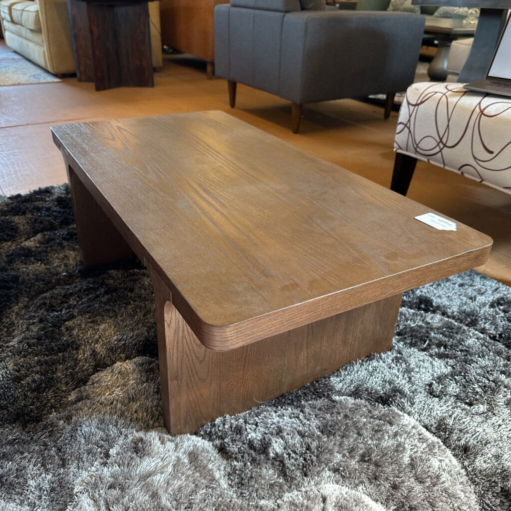 Wooden coffee table in a living room setting with furniture and decor.