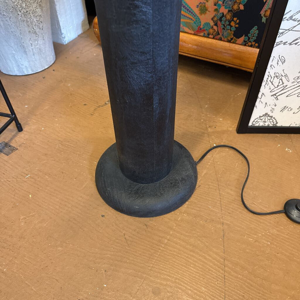 Black cylindrical object on a wooden floor with a blurred background