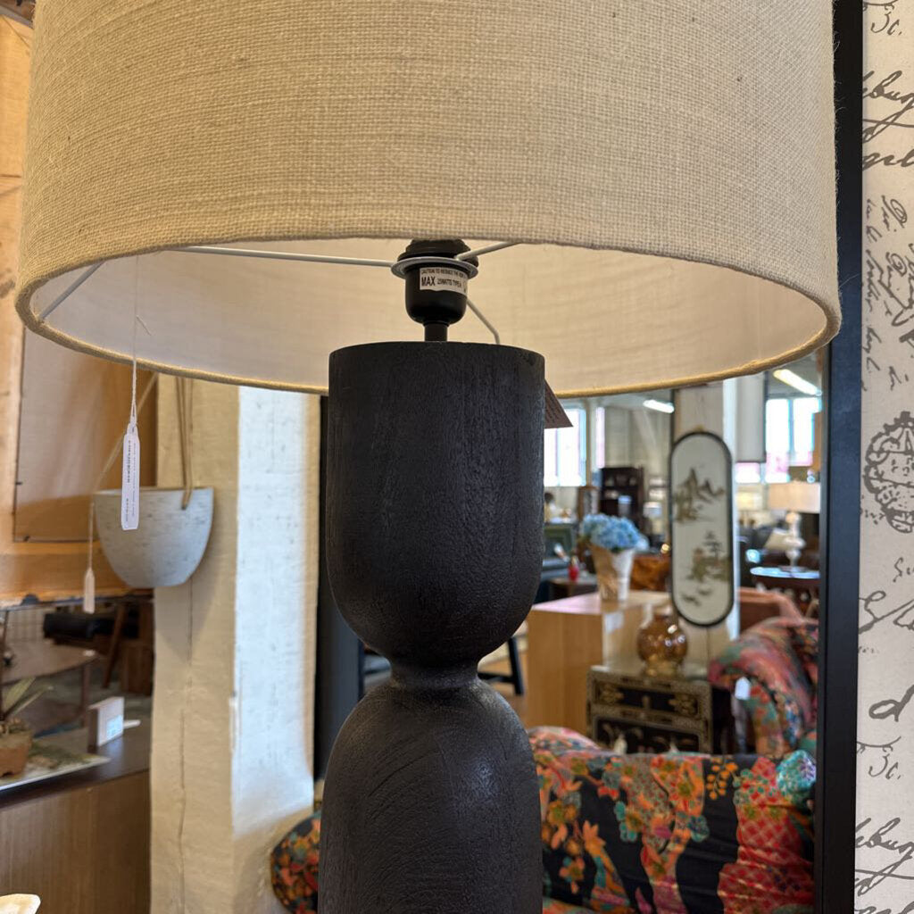 Lamp with a beige shade and black base in a store setting