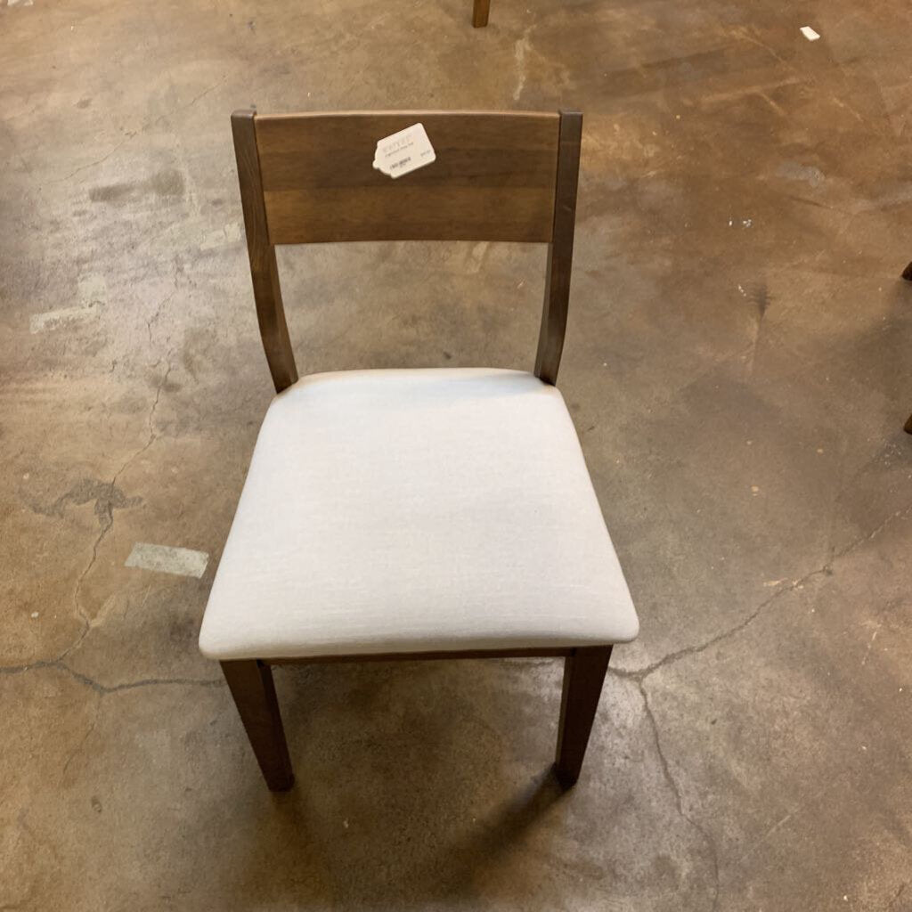 Wooden chair with a white cushion on a concrete floor