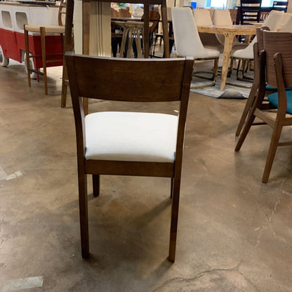 Dining room with wooden chairs and tables on a concrete floor.
