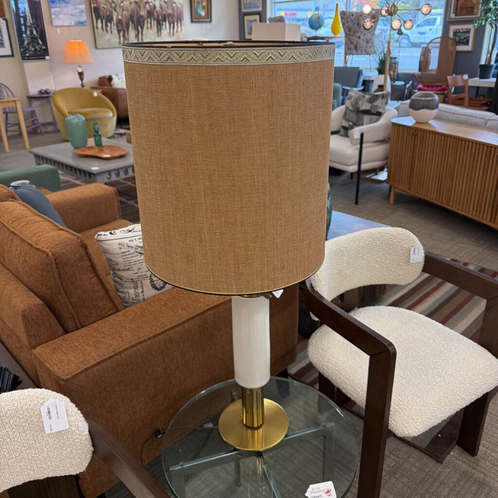 Furniture store interior with a lamp on a glass table, surrounded by chairs and sofas.