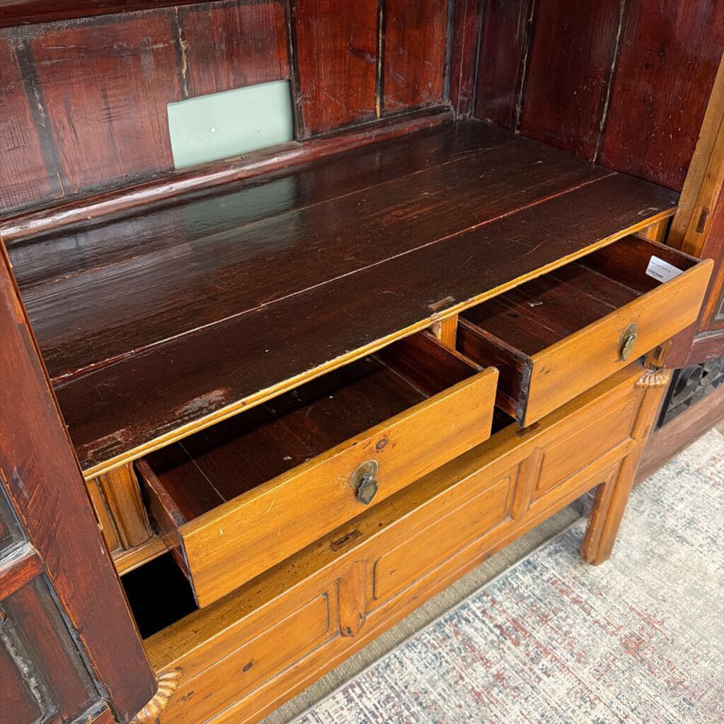 Wooden dresser with open drawers on a textured floor