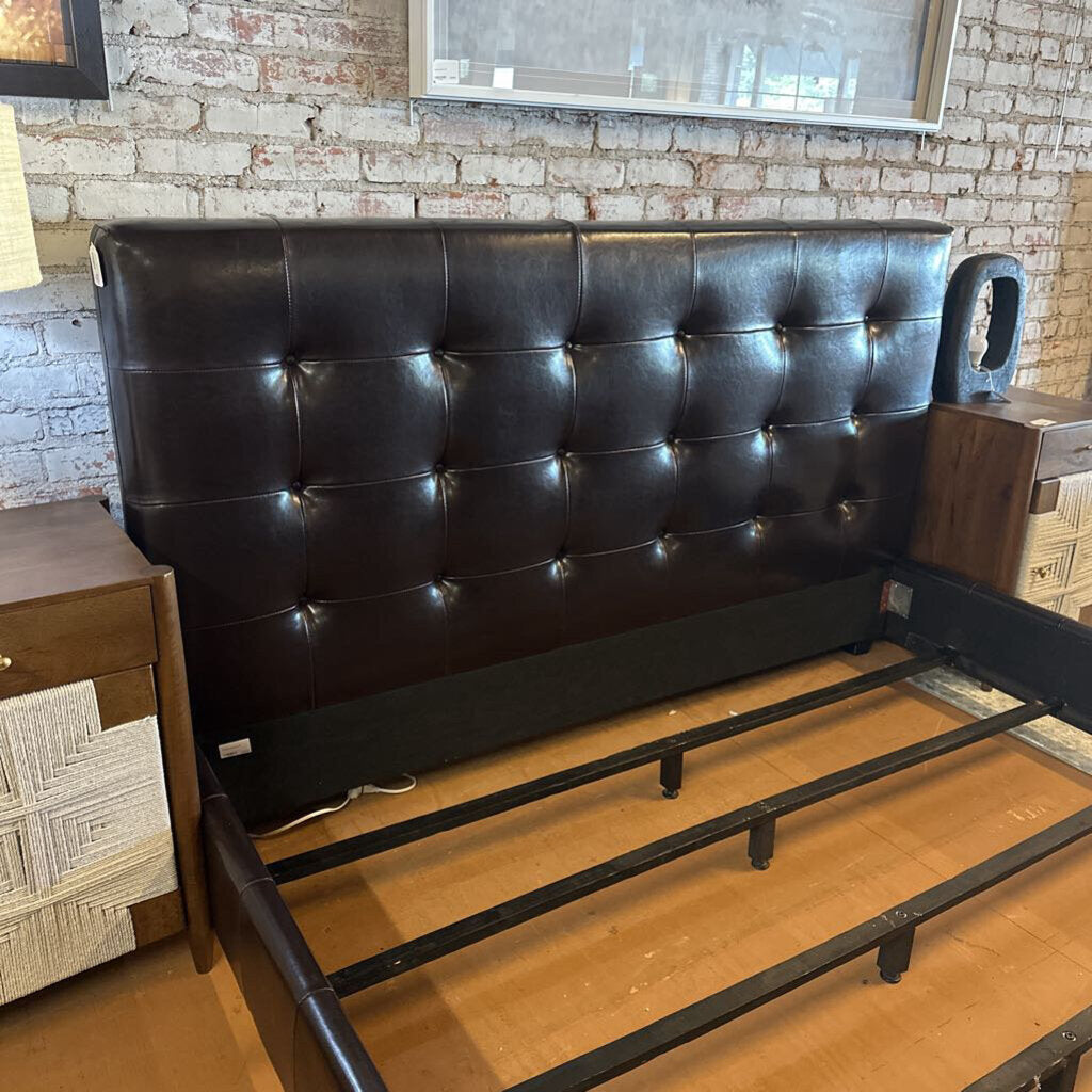 Black tufted headboard on a wooden floor with a brick wall background