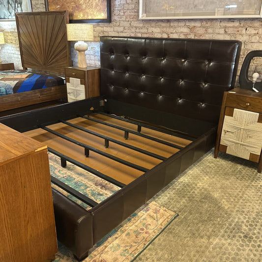 Brown leather bed frame in a bedroom setting with wooden nightstands and lamps.