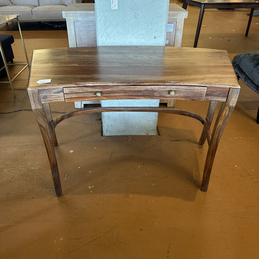 Wooden desk with a single drawer on a wooden floor.