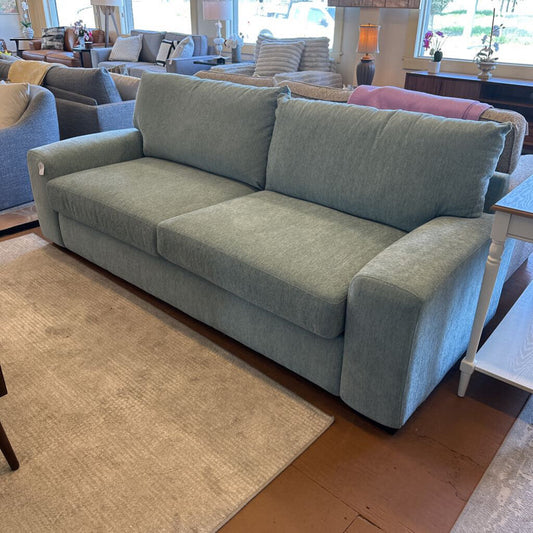 Light blue sofa in a living room setting with other furniture.
