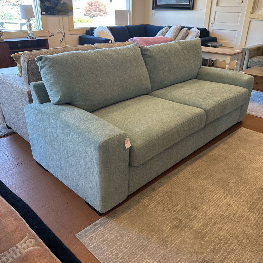 Green sofa in a living room setting with other furniture and decor.