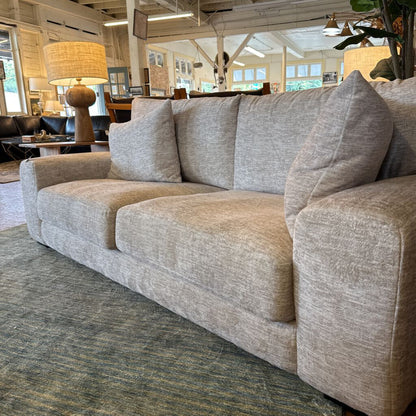 Gray sofa in a room with a lamp and chairs in the background