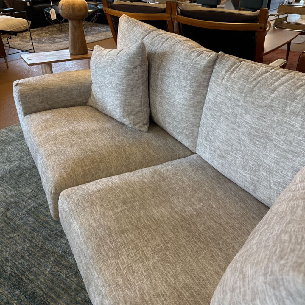Gray sectional sofa in a room with chairs and tables.