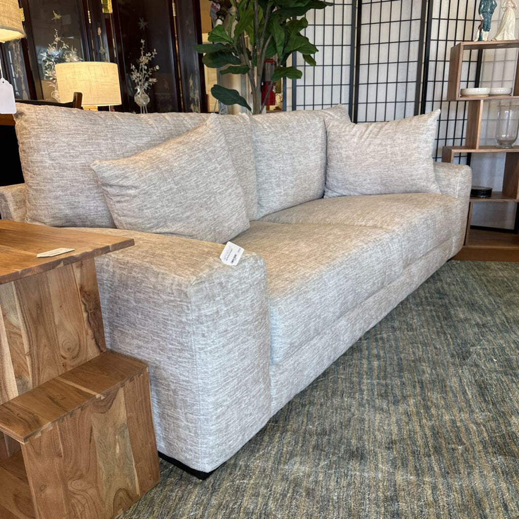 Gray sofa in a room with wooden furniture and decorative items.