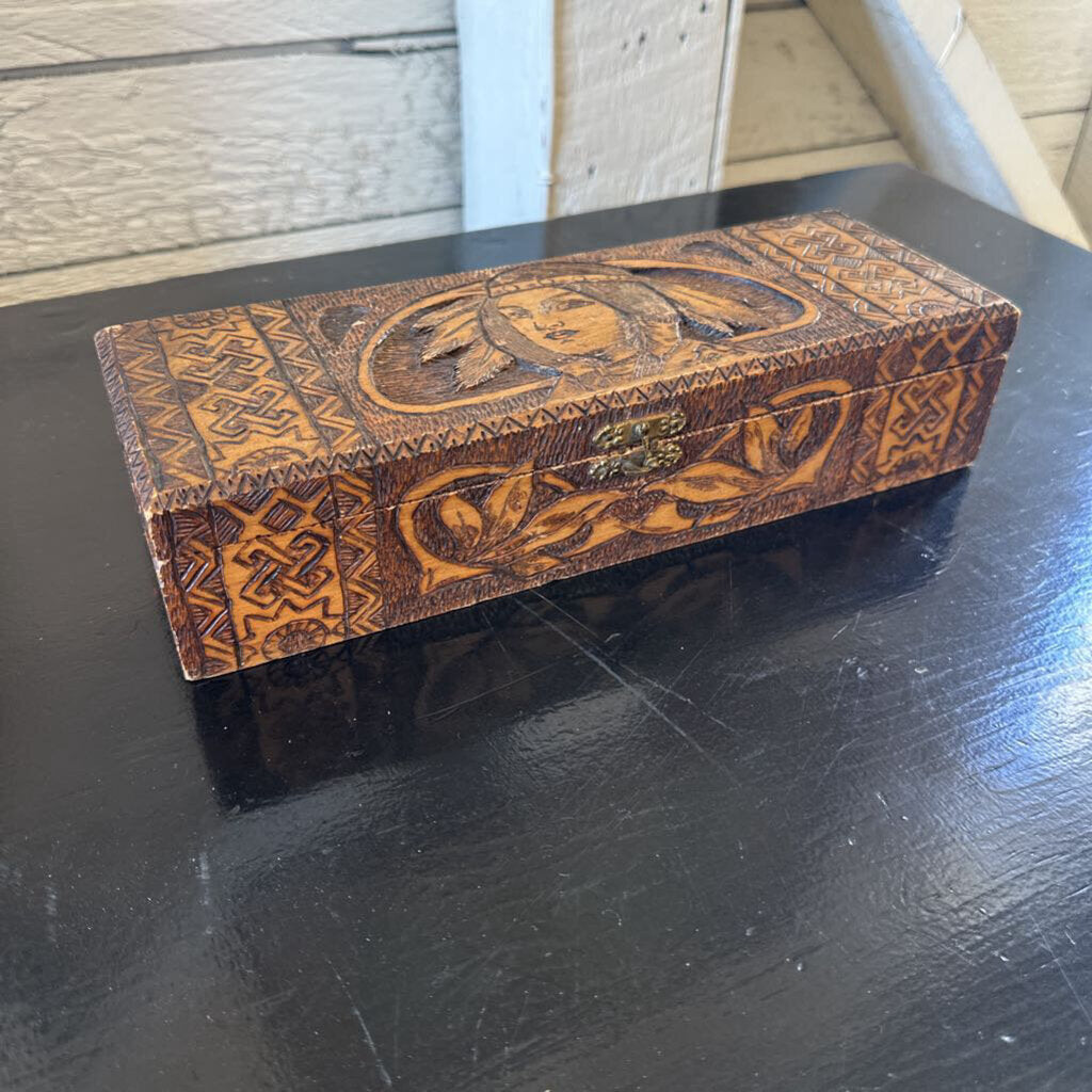 Decorative wooden box with intricate carvings on a black surface