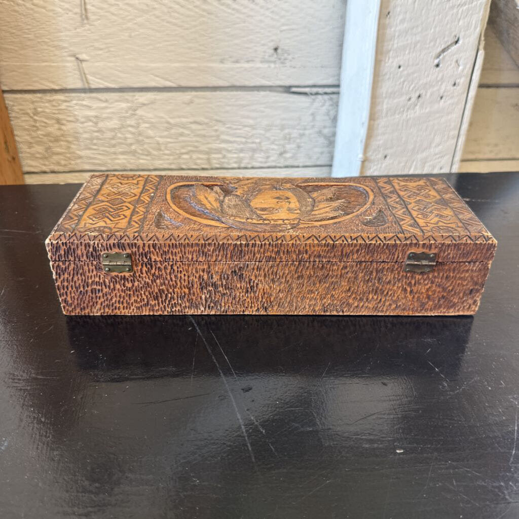 Decorative wooden box with intricate carvings on a dark surface.