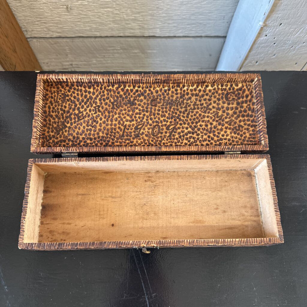 Wooden box with a patterned lid on a dark surface