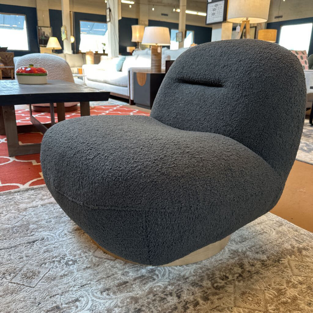 Modern gray chair in a showroom setting with furniture and decor in the background