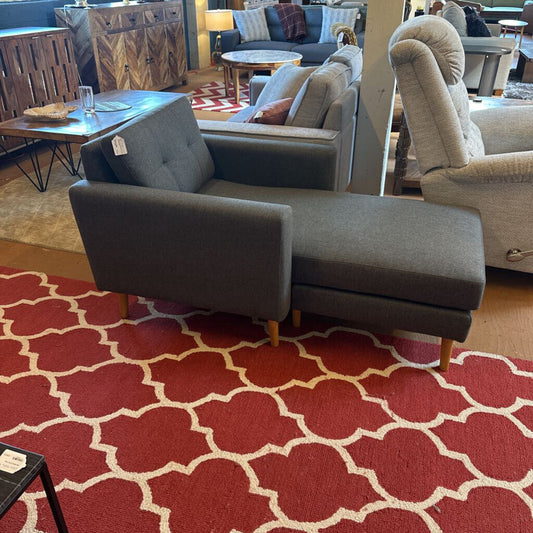 Gray sectional sofa on a red patterned rug in a showroom setting