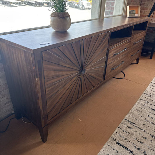 Wooden dresser with starburst design in a room with a rug and window view.