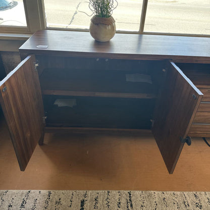Wooden dresser with starburst design in a room with a rug and window view.