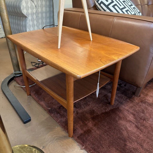 Wooden side table with a tag in front of a brown sofa