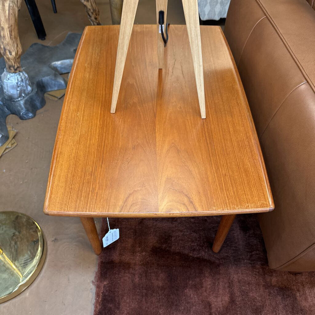 Wooden side table with a tag next to a brown leather sofa.