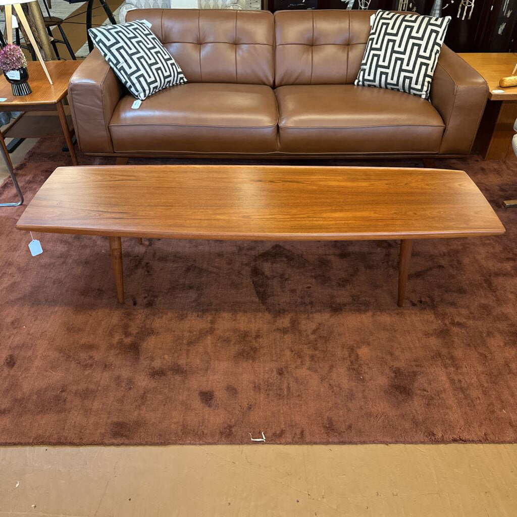 Brown leather sofa with patterned cushions and a wooden coffee table on a brown rug.