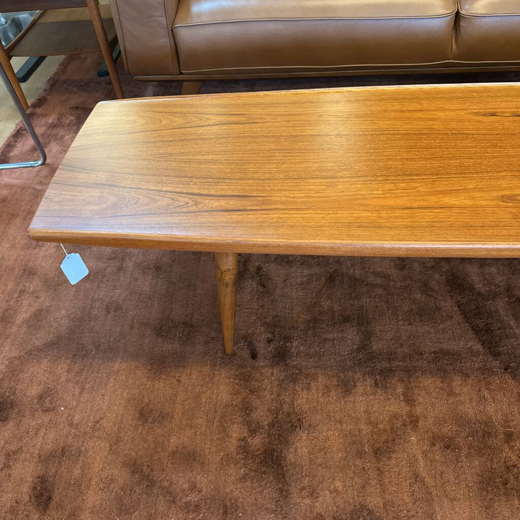 Wooden coffee table with a tag on a brown carpeted floor
