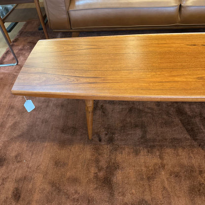 Wooden coffee table with a tag on a brown carpeted floor