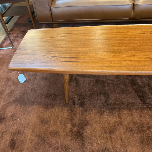 Wooden coffee table with a tag on a brown carpeted floor
