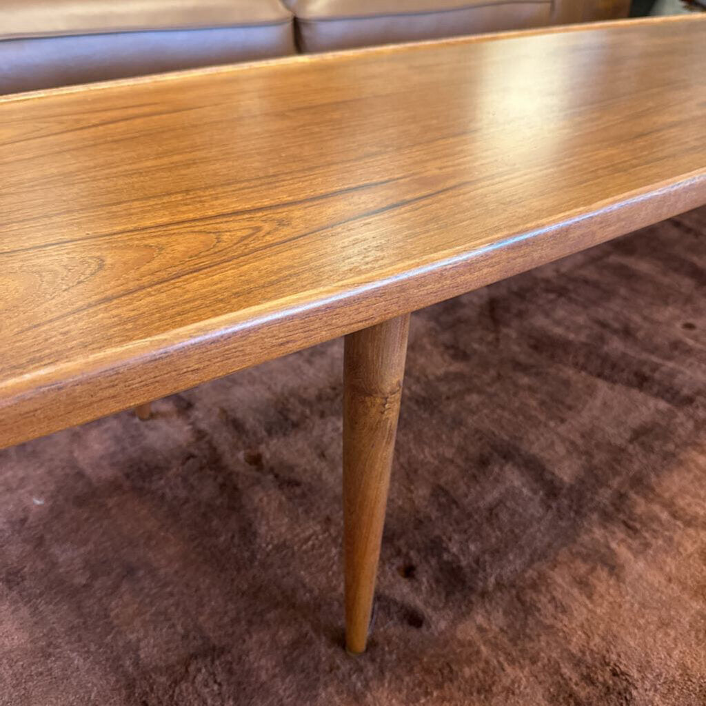 Wooden coffee table with a single leg on a brown carpeted floor
