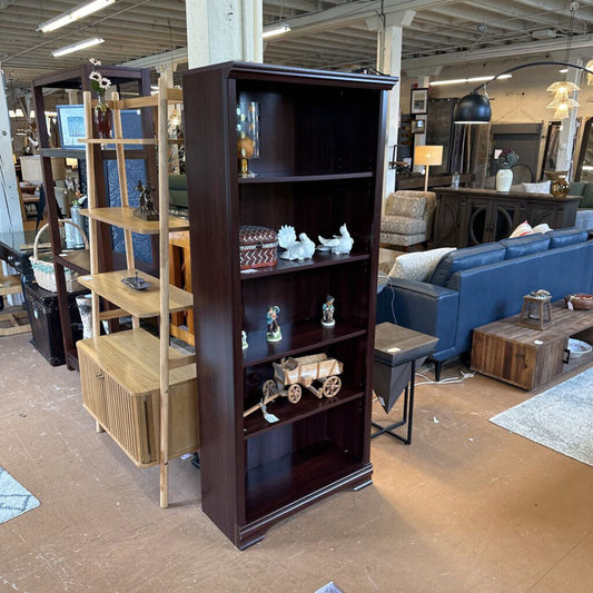 Dark wooden bookshelf in a furniture store with various items on shelves