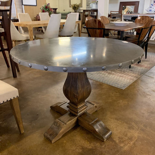 Dining table with metal top and wooden base in a showroom setting