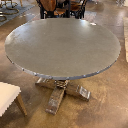 Round metal table with wooden base on a concrete floor
