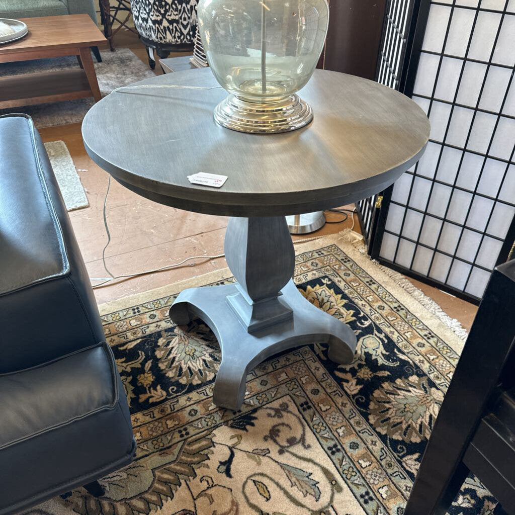 Round side table with a lamp on a patterned rug in a room setting