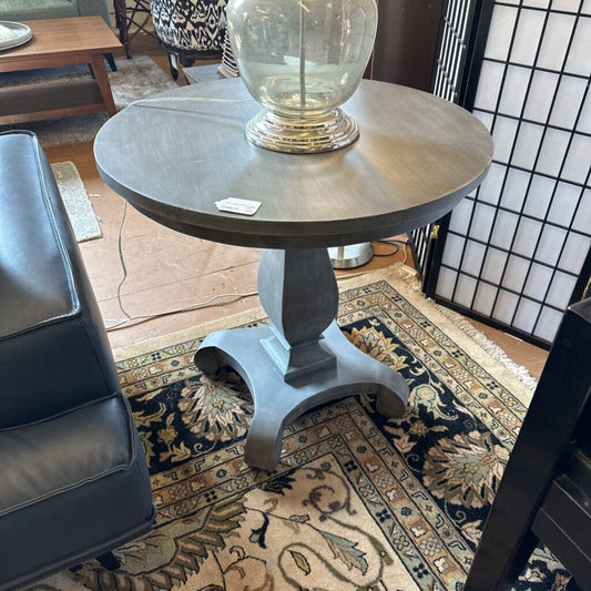 Round side table with a lamp on a patterned rug in a room setting