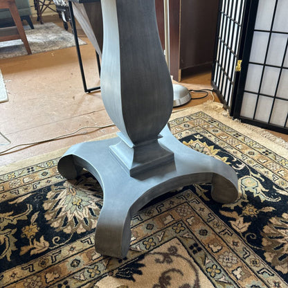 Gray decorative column on a patterned rug in a room with furniture and decor.