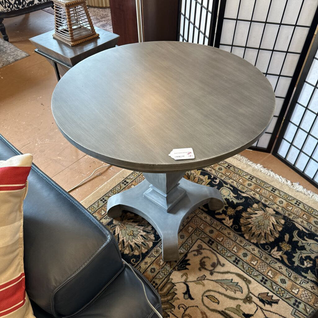 Round wooden table in a room with a sofa and decorative pillows.