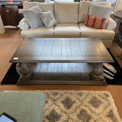 Beige sectional sofa with decorative pillows and a wooden coffee table in a living room setting.