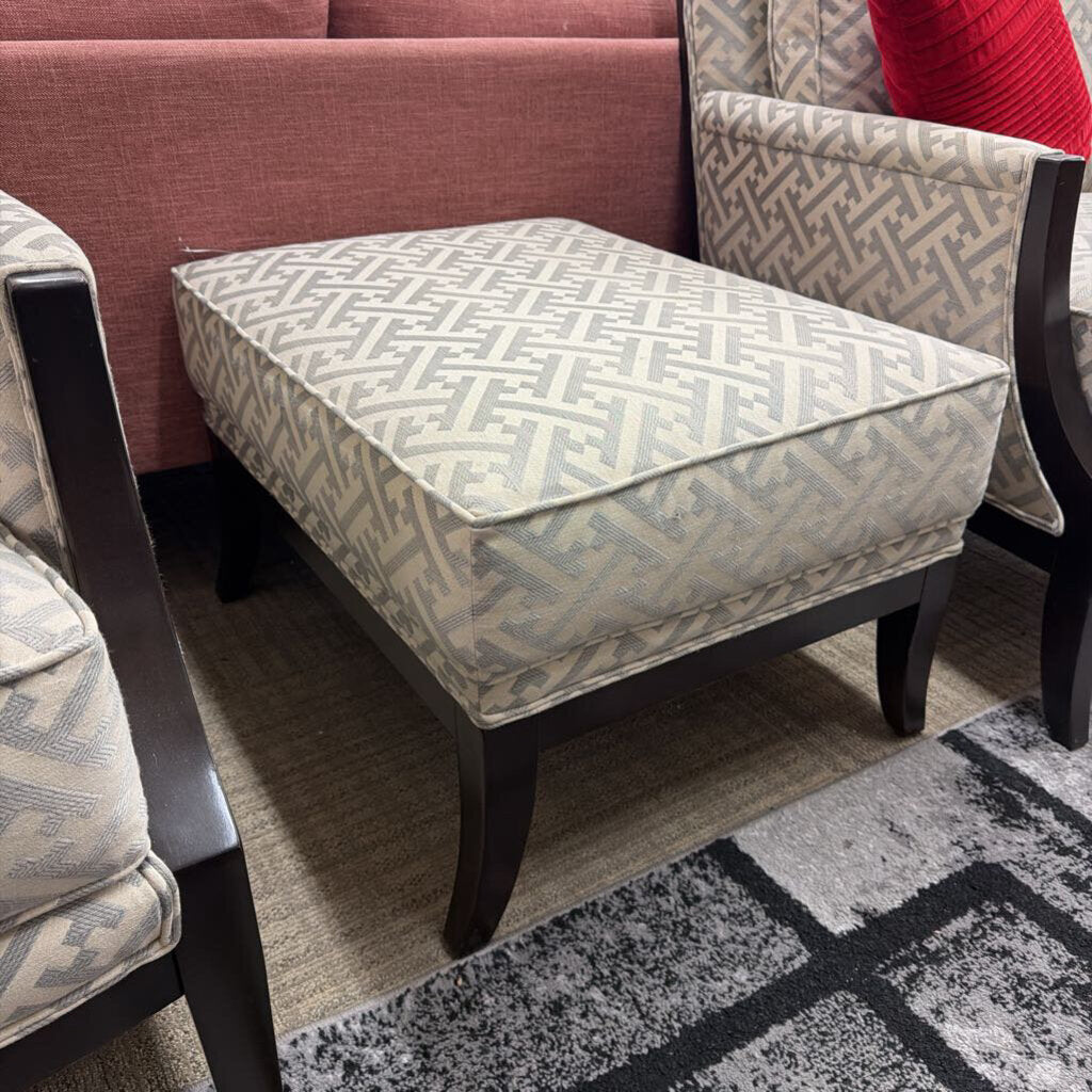 Patterned ottoman with matching chairs on a gray and black patterned rug