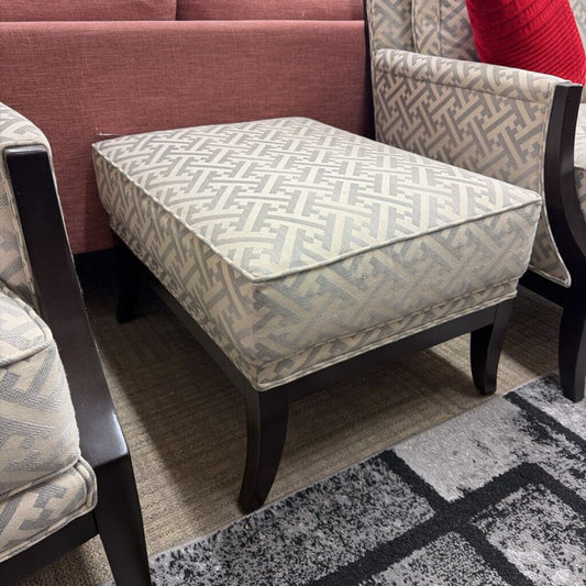 Patterned ottoman with matching chairs on a gray and black patterned rug