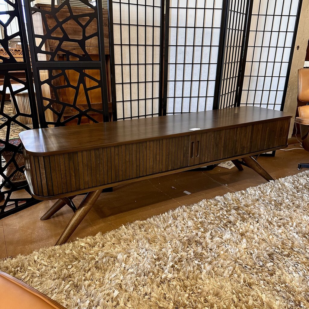 Wooden console table in a room with a textured rug and decorative screen.